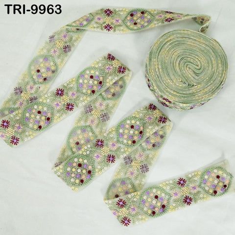 a collection of decorative fabric pieces, including a spool of green thread with a floral pattern and a piece of fabric with a similar floral pattern.