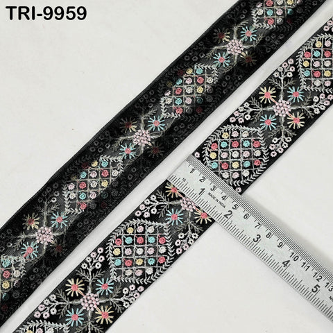 a close-up view of a decorative black fabric with a floral pattern, featuring a ruler for scale.